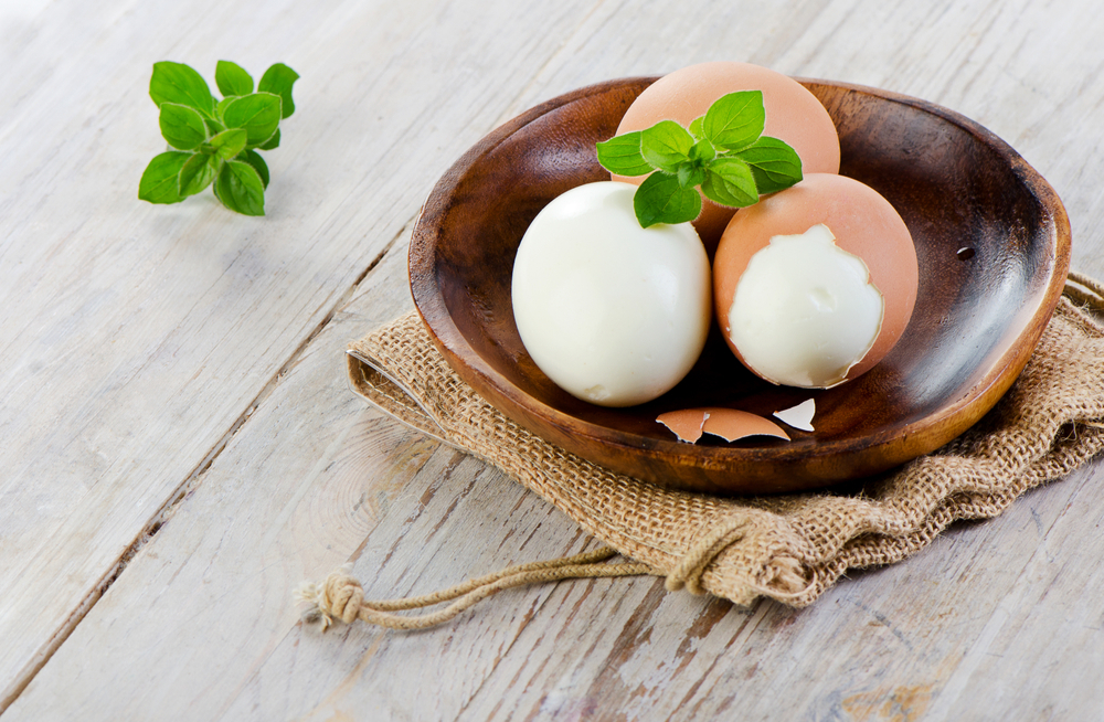 A wooden bowl with three hard-boiled eggs