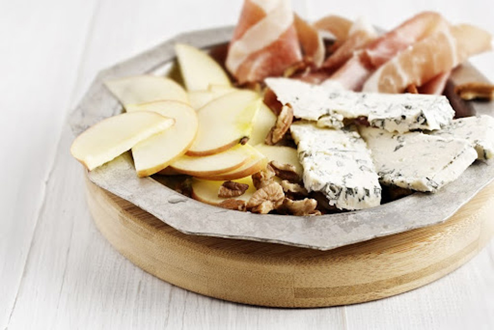 Plate of cheese, nuts, and sliced meat.