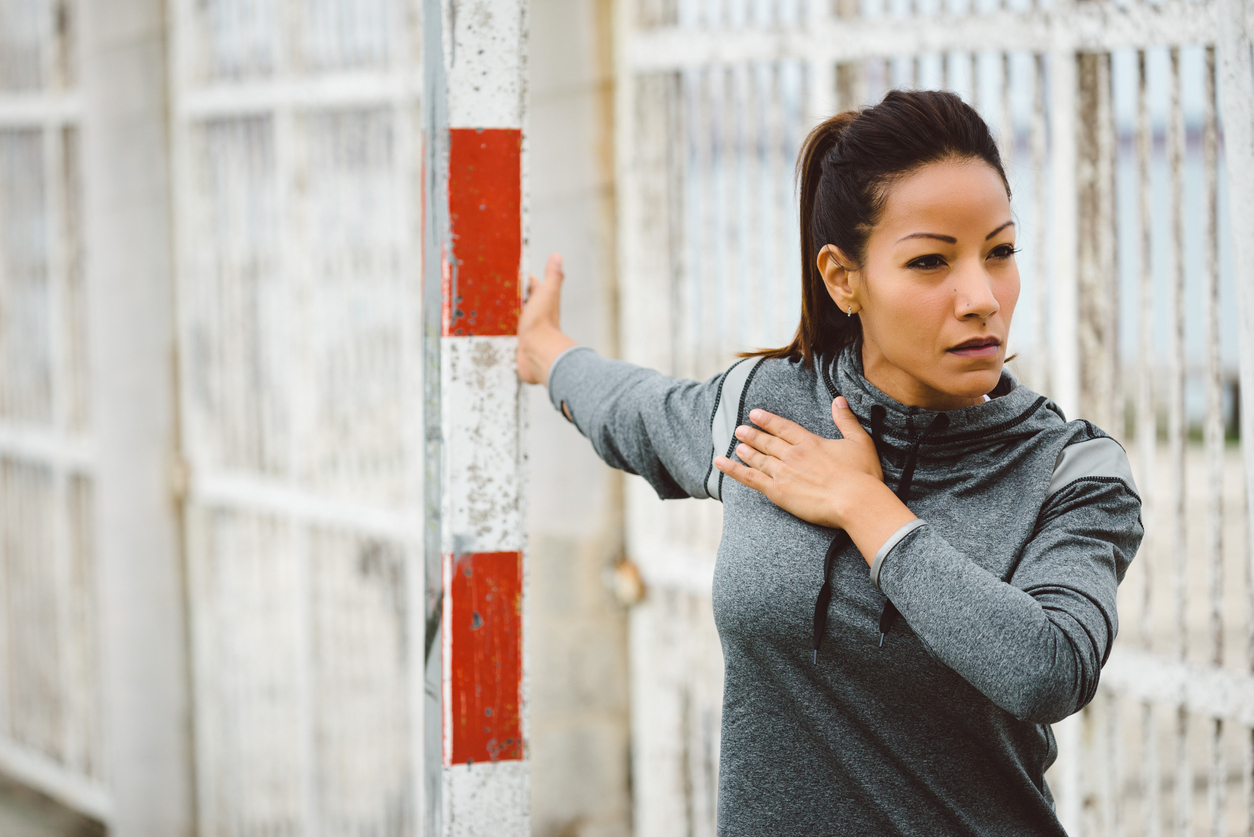 Fitness woman doing chest stretching exercise. Female motivated athlete working out and warming up outdoor. Healthy and sport lifestyle concept.