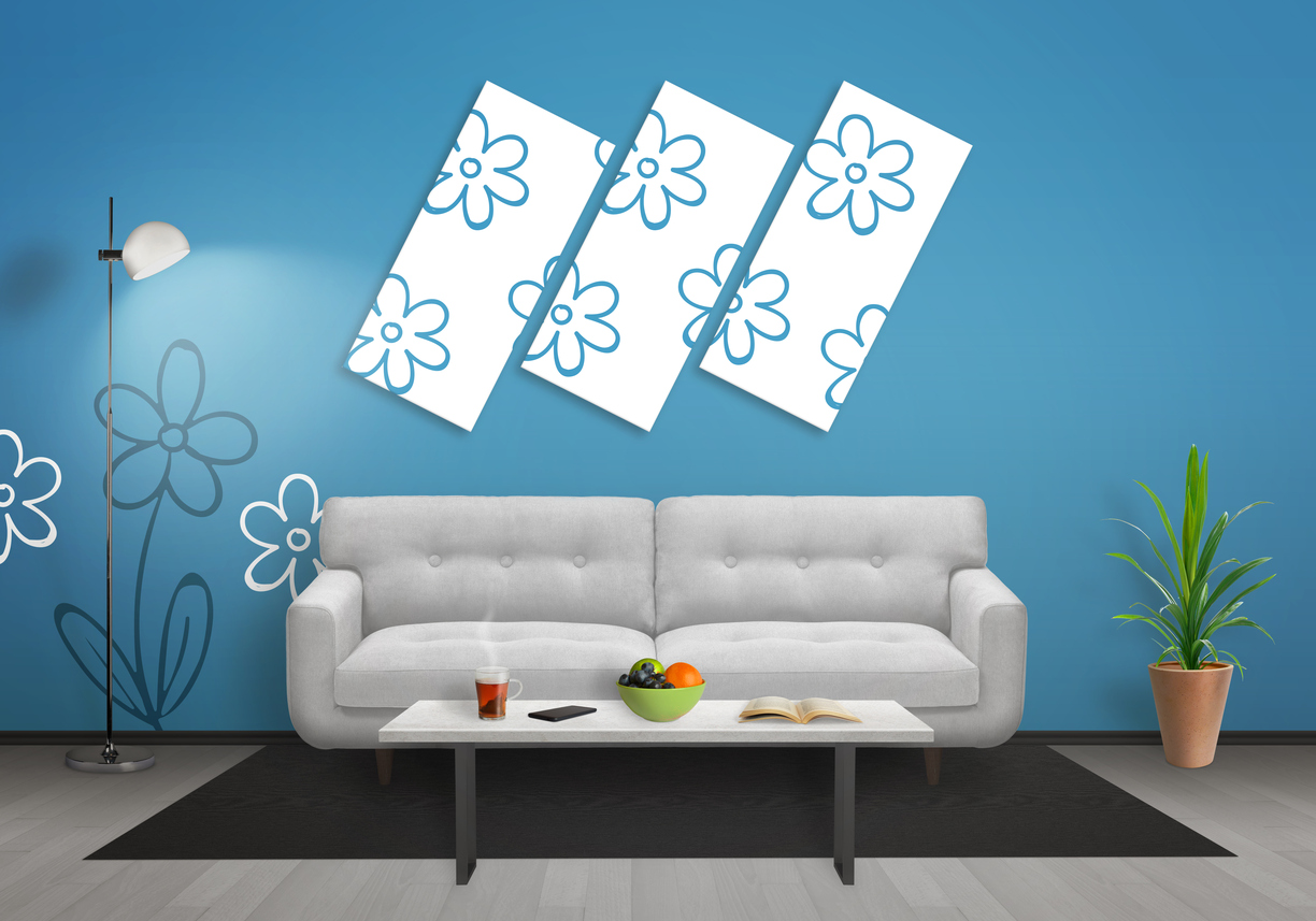 Flowers on foam art canvas in living room. Blue wall with flower wallpaper and gray wooden floor. Sofa, table, lamp and plant in room.