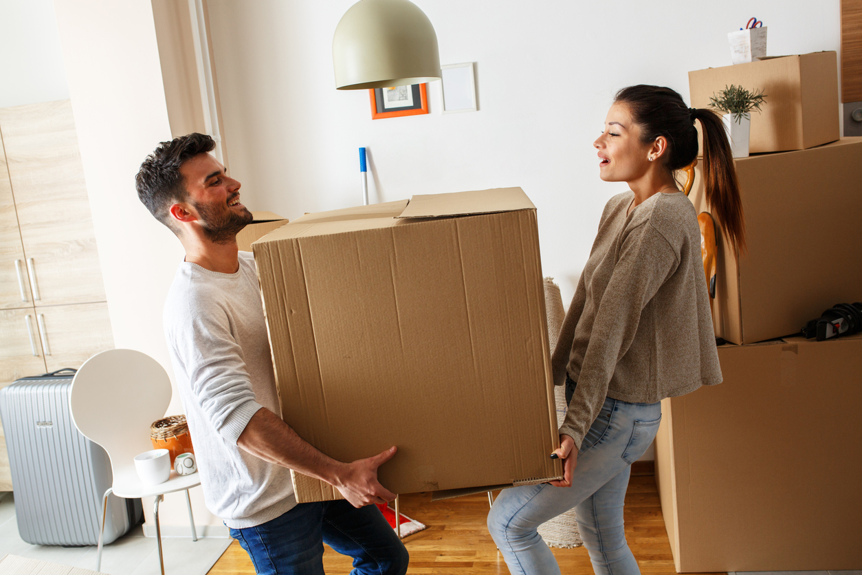 Young couple carrying big cardboard box at new home.Moving house.