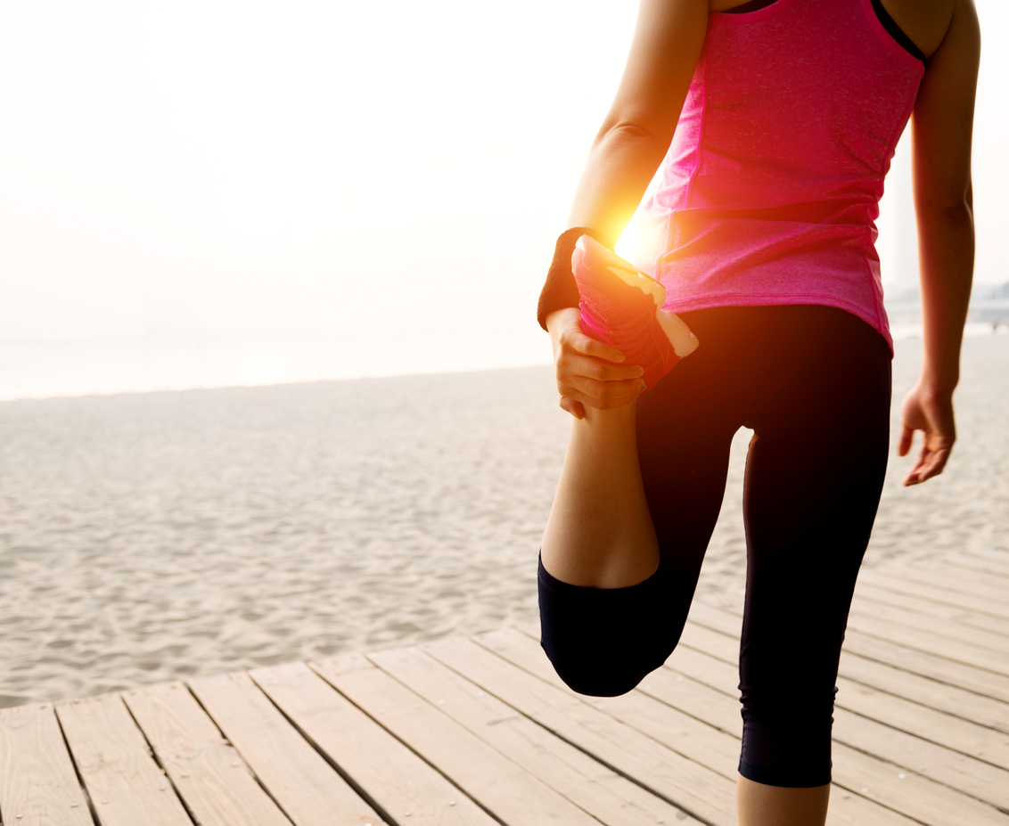 Female runner stretching before run at beach.