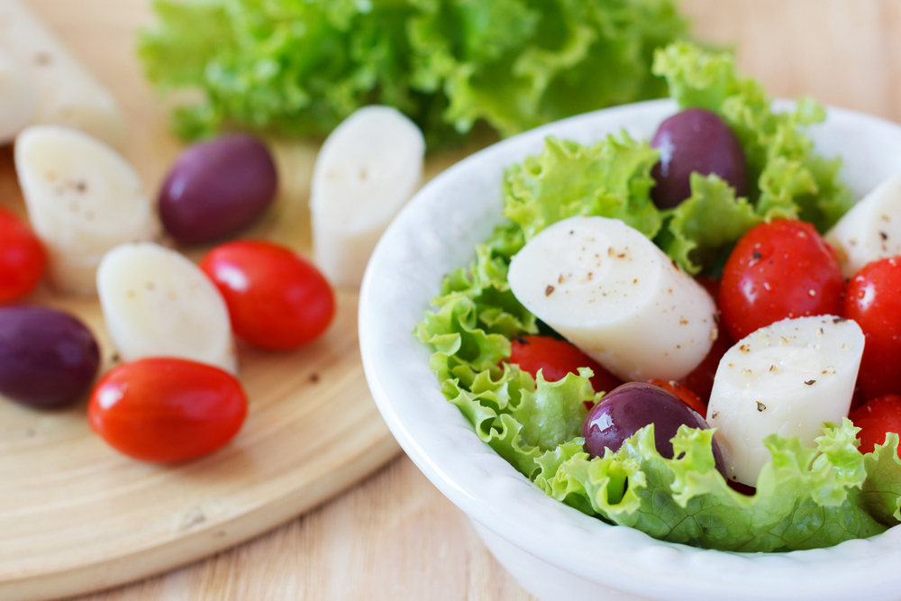 A salad of hearts of palm, lettuce, cherry tomatoes, and olives.