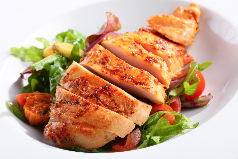 A mouth-watering example of our real marinara chicken breast on a bed of greens with tomatoes.