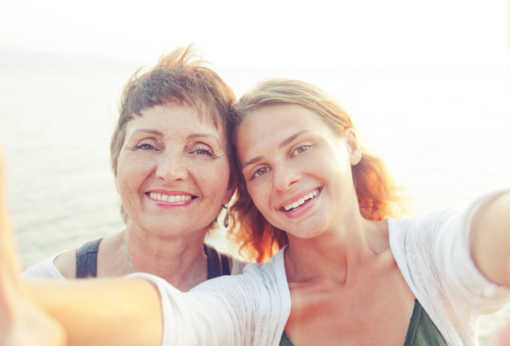 A mom and daughter snap a selfie of themselves at the beach.