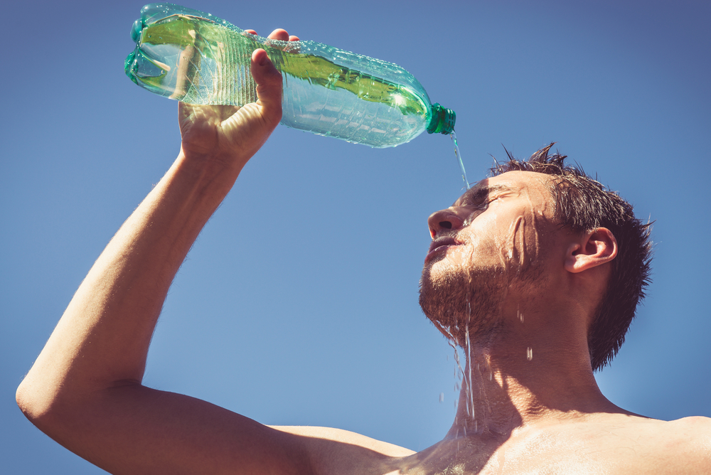 A man pours a drink over his face.