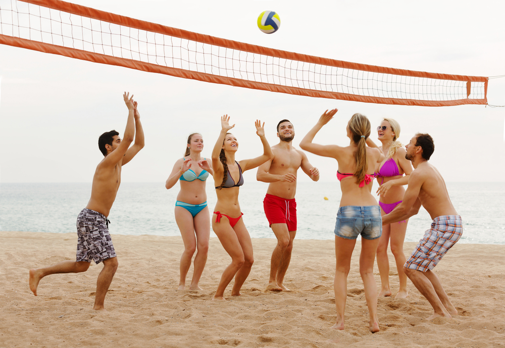 A group of Spring Break vacationers stay active at the resort by playing a fun game of beach volleyball.
