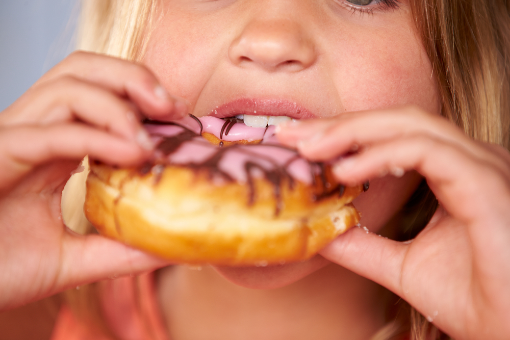 A little girl eating a doughnut as our country suffers from an epidemic of obesity.