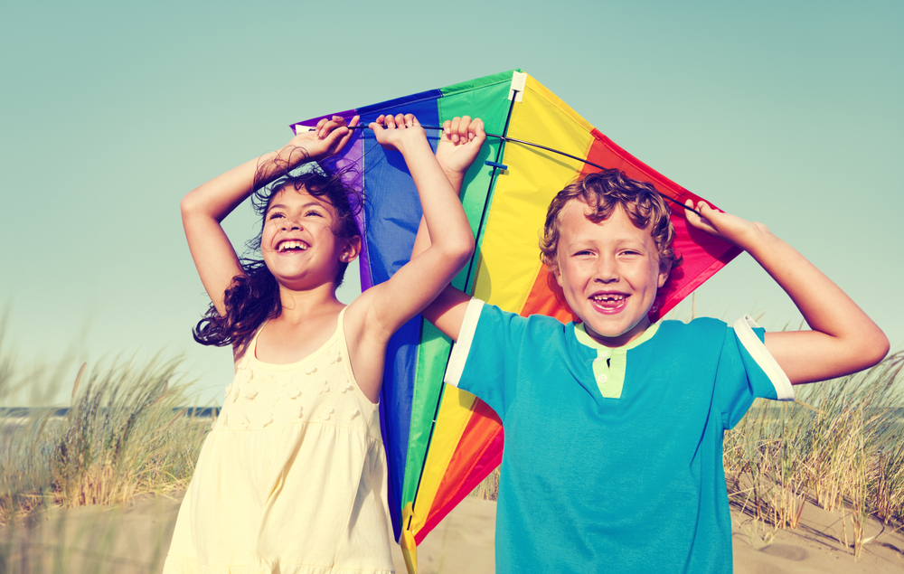A healthy little girl and boy play with a rainbow-colored kite. 