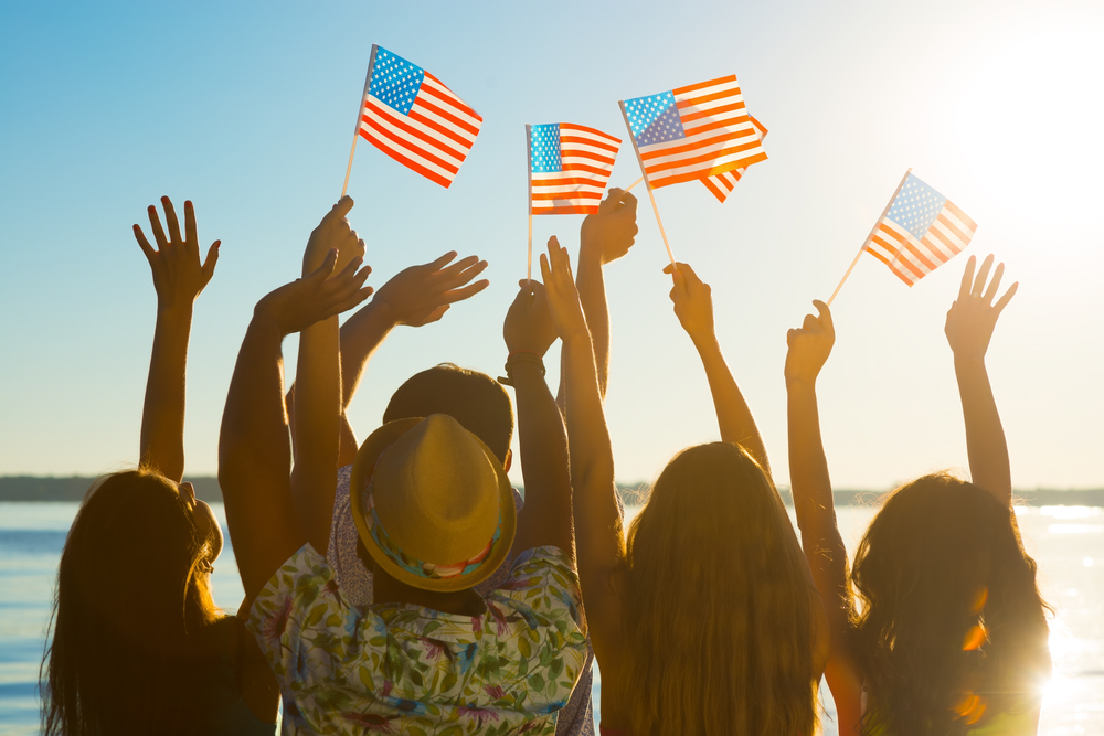 A group of friends waving flags on the beach in celebration of a healthy Memorial Day with Personal Trainer Food.
