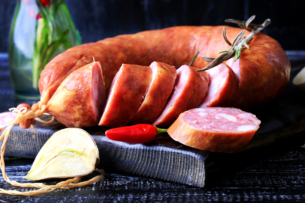 A sliced large Polish sausage, presented with herbs.