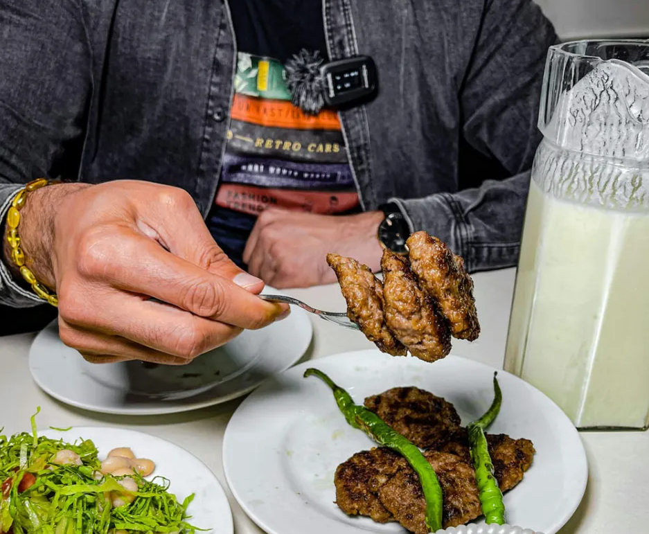 Man eating beef nuggets and green beans with a protein shake. There’s a side of chickpea salad.