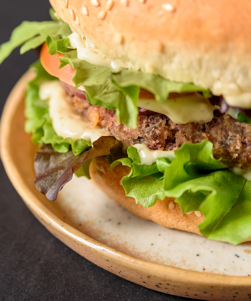 A lettuce bun burger with tomatoes, eggs, and cheese.